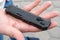 Closeup view of a black pocket folding knife lying on the palm