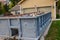 Closeup view of a blue dumpster filled with construction debris in the driveway of a yellow house in front of the garage doors