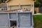 Closeup view of a blue dumpster filled with construction debris in the driveway of a yellow house in front of the garage doors