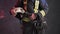 Closeup view of a brave firefighter in special uniform holds protective helmet standing against a gray wall