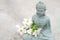 Closeup view of Buddha statuette with blooming cherry tree branch on concrete background with copy space