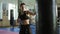 Closeup view of caucasian female kickboxer hitting the punching bag with her hands and legs in the gym alone. Tough