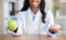 Closeup view of dietitian's hands holding fresh apple and donut at table in medical office. Dieting concept