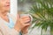 Closeup view of elderly woman with cup of tea in nursing home, space for text. Assisting