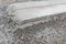 Closeup view of the end of a section of extruded concrete curbing on a bed of heavy gravel, new road construction, creative copy s