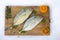 Closeup view of fresh Malabar Trevally fish or Nakedshield Kingfish decorated with spices abd herbs on a wooden pad White