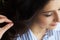 Closeup view of the hand and comb of a hairstylist combing a new hairstyle on a customer head in hair salon.