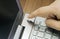 Closeup view of a hand with a finger, press the power button on metallic silver laptop keyboard, lying on a wooden mat