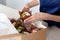 Closeup view of hands of female confectioner or baker packing tasty decorated muffins with cream top to delivery box.