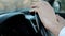 Closeup view on hands of man on steering wheel inside car.