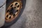 A closeup view of a heavily used car tyre that seems abandoned for a long time. There are also rusted rim, hubcap and screws that