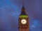 Closeup view of the illuminated Big Ben clock of the Elizabeth tower in London at dusk.