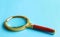 Closeup view of magnifier glass on blue background, space for text. Find keywords concept