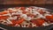 Closeup view of making a pizza with ingredients appearing on the baking plate