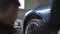 Closeup view of mechanic lifts the car in the service using a lift. Footage. Over the shoulder, blurred silhouette of a
