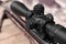 Closeup view of modern powerful sniper rifle with telescopic sight on blurred background