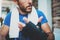 Closeup view of Muscular athlete man prepairing hands for hard kickboxing training session in gym. Young athlete tying