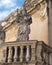 Closeup view of one of 3 saint statues on a balcony at the entrance to the Piazza del Duomo, Lecce