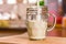 Closeup view pouring fresh kefir probiotik drink into half full clear glass cup on kitchen table