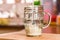 Closeup view pouring fresh kefir probiotik drink into one quarter full clear glass cup on kitchen table