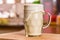 Closeup view pouring fresh kefir probiotik drink into overfilled clear glass cup on kitchen table