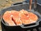 A closeup view of salmon steaks being grilled on a cast iron skillet