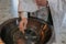 Closeup view to the priest hand holding cross and baptismal font for ceremony of the baptism of a newborn baby in Orthodox Church