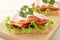 Closeup view of toasts,lettuce,tomato,cold cuts on cutting board