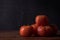 Closeup view of tomatoes on a wooden cutting board with waterdrops on a black background