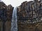 Closeup view of the top of stunning water fall Svartifoss with hexagonal basalt columns and icicles in Skaftafell.