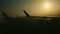 Closeup view from window on plane wing against big aircraft silhouette on sunrise