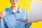 Closeup view of woman in the blue shurt holding laptop and credit card.