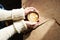 Closeup view woman hands holding cup of coffee at wooden slab table, top view, sunny cafe, warm atmosphere