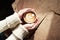Closeup view woman hands holding cup of coffee at wooden slab table, top view, sunny cafe, warm atmosphere.