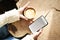 Closeup view woman hands using mobile smartphone and cup of coffee. Space mockup for design layout. Sunlight, slab wooden table.