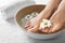 Closeup view of woman soaking her feet in dish with water and flowers on white towel.