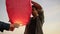 Closeup view of young multiethnic couple holding red paper lantern before launching. Attractive woman with her african