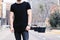 Closeup view of young muscular man wearing black tshirt and jeans posing on the street of the modern city. Blurred