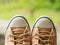 Closeup of vintage soft brown woman sneaker shoes on blur green nature in background. Travel adventure and journey concept