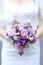 Closeup vioelt bouquet of flowers in fiancee hands.