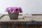 Closeup of violet summer flowers in a nice small metal vase on a rustic wooden piece of furniture