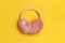 Closeup of warm fluffy pink ear muffs on a yellow background