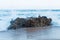 Closeup of waves hitting a rock at a shore creating water splash and spray