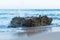 Closeup of waves hitting a rock at a shore creating water splash and spray