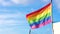 Closeup waving gay pride rainbow flag, symbol of the LGBT community on a pride in a European city. On blue sky. Human