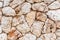 Closeup of a weathered stone wall covered with an intricate mosaic of variously-sized rocks.