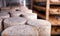 Closeup of wheels of sheep cheese on shelves in ripening room