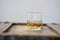 Closeup of a whisky glass with golden shimmering whisky on a shabby wooden rustic table