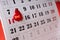 Closeup of white calendar page and red number 14 february.Valentines Day.Push pin and decorative heart on the calendar