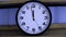 Closeup of White Clock Face on white wall clock, arrows show 00:00 at night.